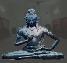 Seated bronze figure wearing a crown, on display in a museum