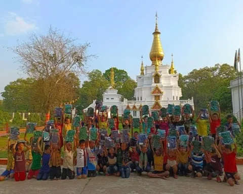 Children holding up their new books in front of the pagoda