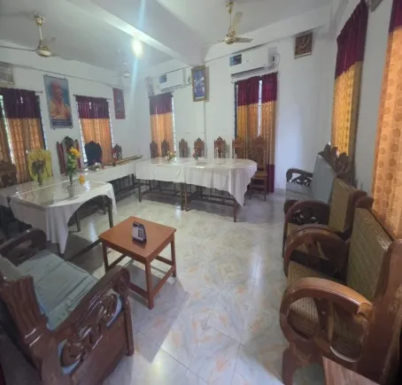 Lounge of the guest house with wooden sofas and a dining table