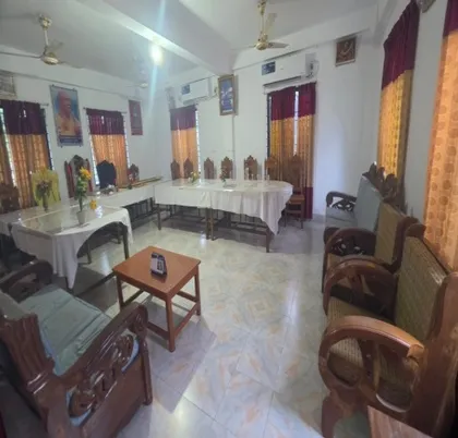 Lounge of the guest house with wooden sofas and a dining table