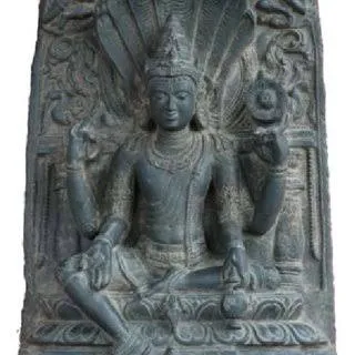 Stone relief of a seated deity beneath a serpent canopy